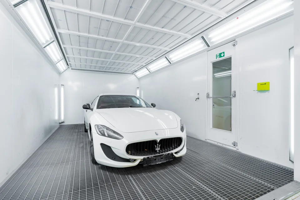 Білий Maserati у світлій професійній фарбувальній камері — стокова фотографія