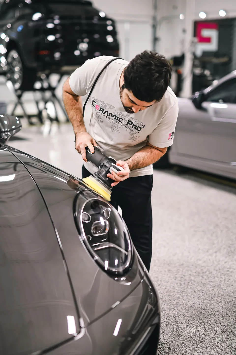 Спеціаліст полірує Porsche у світлому обладнаному детейлінг-центрі — стокова фотографія